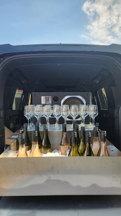 De geopende achterklep van de HOUSEWINE Defender met wijnglazen en gekoelde flessen.
